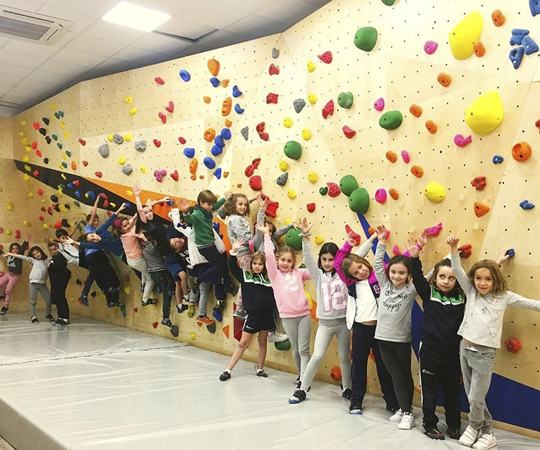 grupo de niños delante de un muro de escalada