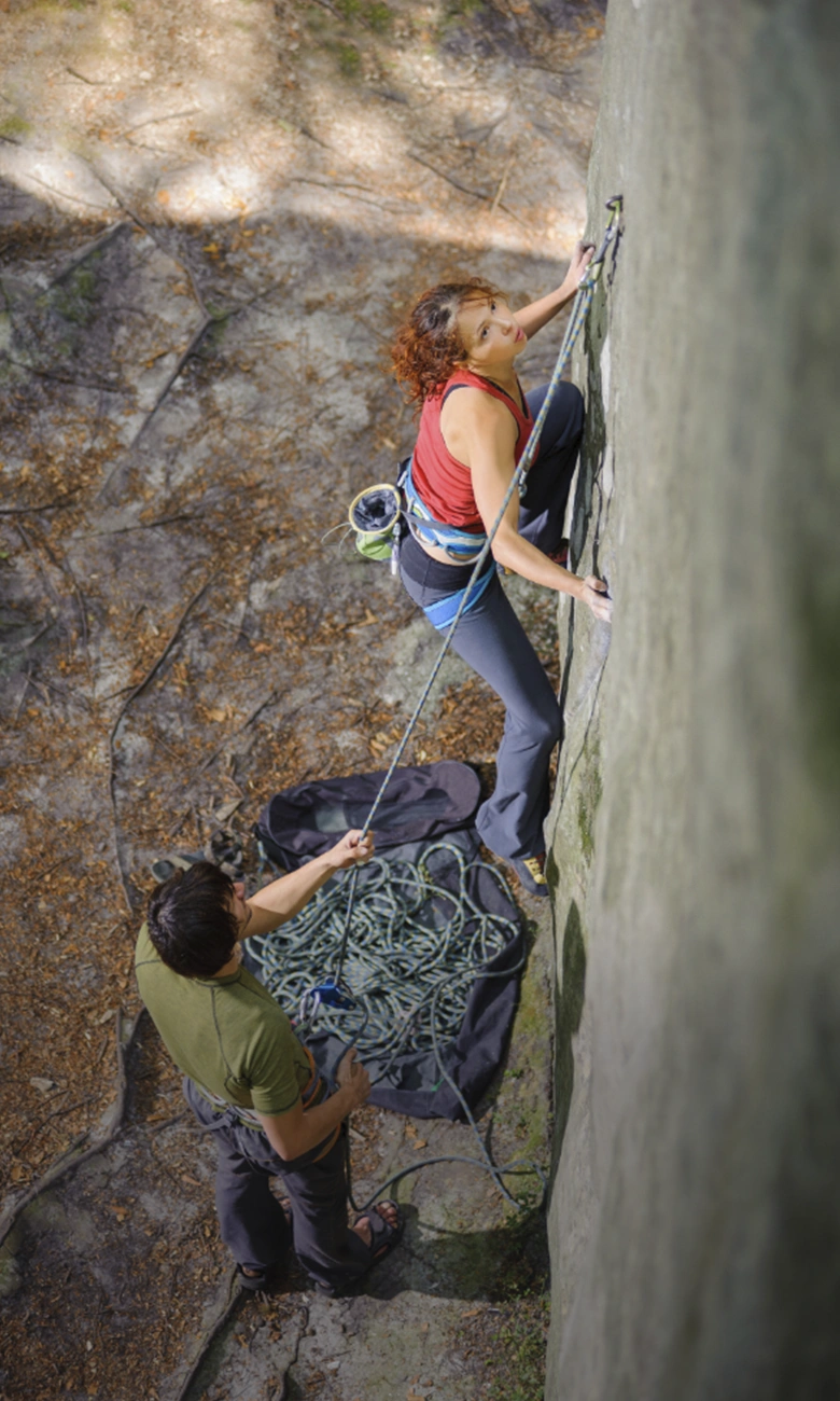 mujer escalando en roca con monitor debajo