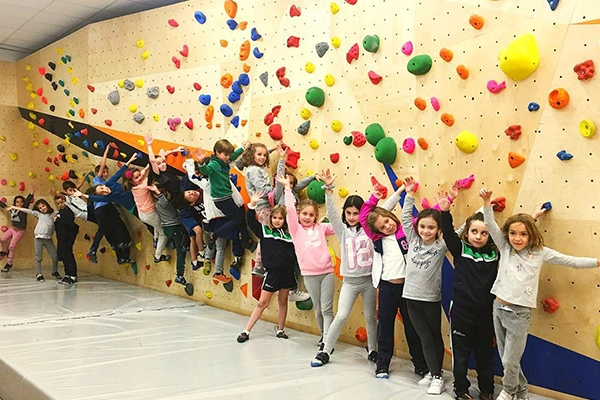 niños y niñas delante muro escalada