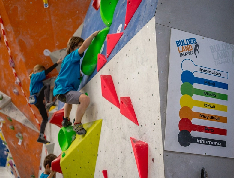 ninos y niñas escalando en muro indoor